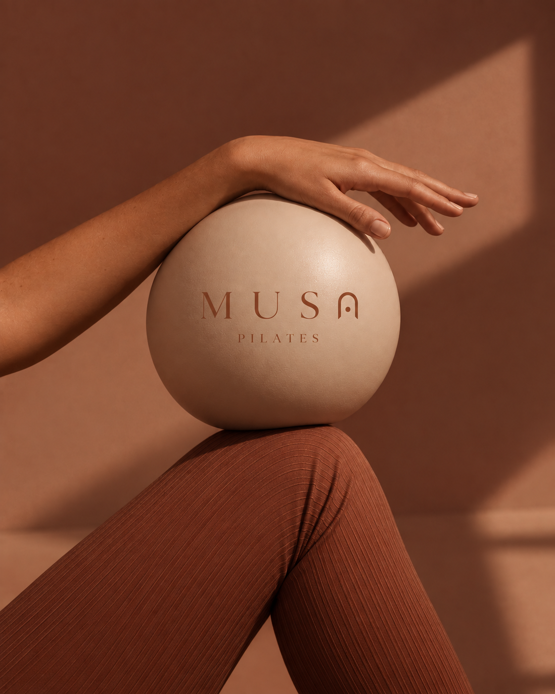 Hand resting on a Musa Pilates ball
